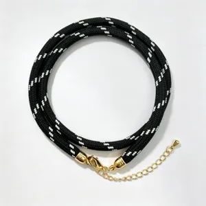 Black and white braided cord necklace detail showcasing texture and gold metal clasp.