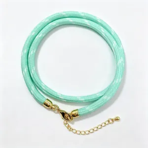 Close-up detail of mint green braided cord necklace with gold lobster clasp and extension chain.