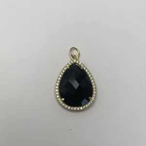 Detailaufnahme des tropfenförmigen schwarzen Steinanhängers mit glänzendem goldenem Rand.