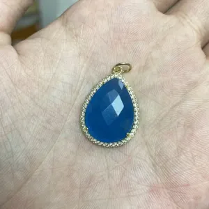 Detaillierte Nahaufnahme des blauen Tropfenanhängers mit Zirkonrand und Goldfassung.