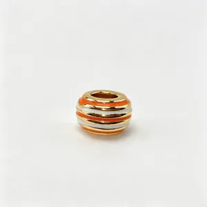 Close-up of gold plated colorful striped charm bead, stylish DIY jewelry accessory detail.