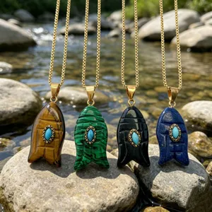 Gros plan de quatre colliers pendentifs poisson en pierre naturelle sur des rochers.