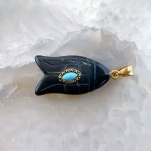 Vue rapprochée du pendentif poisson en pierre noire avec turquoise et anneau doré.