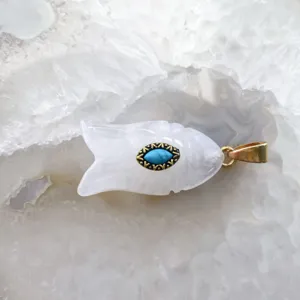 Détail en gros plan du pendentif poisson en pierre naturelle blanche avec incrustation.