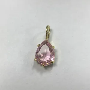 Dettaglio ravvicinato di un ciondolo in zircone rosa a goccia con raffinata montatura dorata.