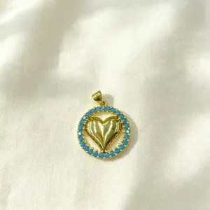 Gold heart pendant with blue zircon stones, elegant micro pave circular necklace accessory.