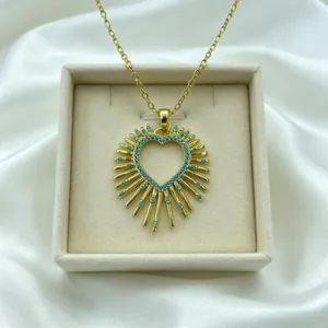Detailed view of gold sunburst heart necklace pendant featuring turquoise zirconia stones.