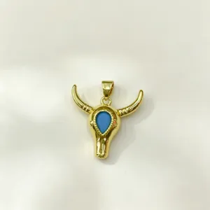 Pendentif crâne de taureau doré avec accent de pierre bleue, accessoire de bijoux détaillé.