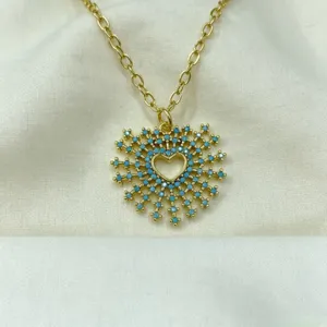 Detailed shot of gold-plated necklace featuring a unique heart starburst pendant with blue stones.