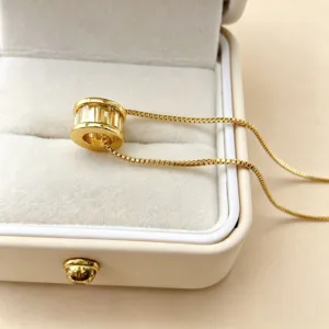 Vergulde cilindrische hanger ketting met sprankelende zirkonias stenen in doos.