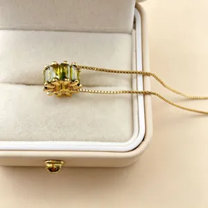 Green cubic zirconia wheel bead pendant close-up, shiny gold plated jewelry detail view.
