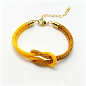 Detailed close-up of the two-color braided rope bracelet featuring a knot and gold chain.