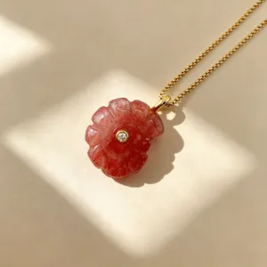 Gros plan sur le pendentif coquillage sculpté avec une pierre centrale sur chaîne dorée.