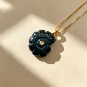 Vue détaillée d'un collier pendentif en pierre naturelle de conque sculptée noire avec chaîne or.