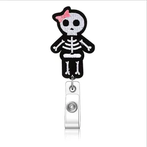 Retractable badge reel featuring a cute embroidered skeleton felt patch with a pink bow accent.