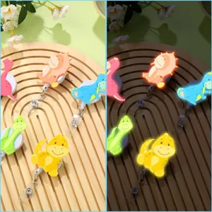 Detail view showing cute dinosaur retractable badge reels on a wooden board with glow.