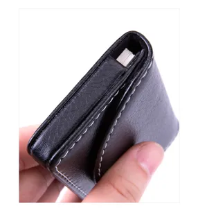 Close-up detail shot of black leather business card holder with white stitching and magnetic closure.