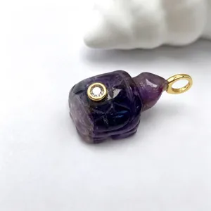 Gros plan detaille sur un pendentif tortue en amethyst naturelle avec beliere doree.