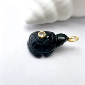 Détail macro en gros plan d'un magnifique pendentif tortue en pierre noire sculptée.