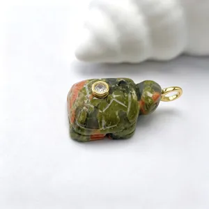 Gros plan détaillé d'un pendentif tortue en pierre naturelle sculptée avec belière dorée.