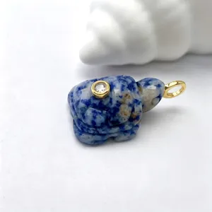 Gros plan sur un pendentif tortue sculpté en pierre naturelle avec anneau doré.