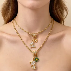 Gold-plated multi-layer necklace with cubic zirconia tube beads, daisy and butterfly charms.