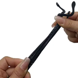 Gros plan détaillé du jouet serpent en caoutchouc noir flexible, montrant texture réaliste et élasticité.