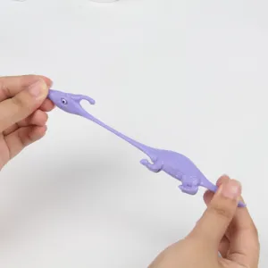 Gros plan du dinosaure jouet violet extensible étiré, montrant sa matière en caoutchouc souple.