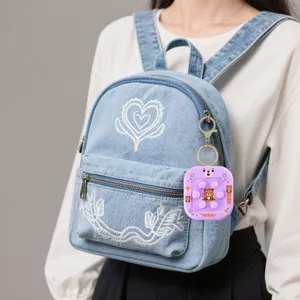 Vue détaillée du joli porte-clés jeu pop it accroché à un sac à dos en jean.