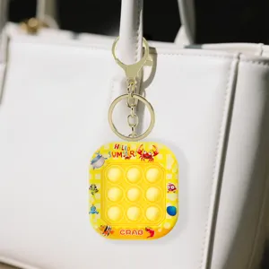 Nahaufnahme eines gelben Mini-Pop-It-Spielkonsolen-Schlüsselanhängers an einer Handtasche.
