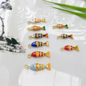 Close-up van kleurrijke geëmailleerde vis bedels, gedetailleerde koperen DIY hanger accessoires.