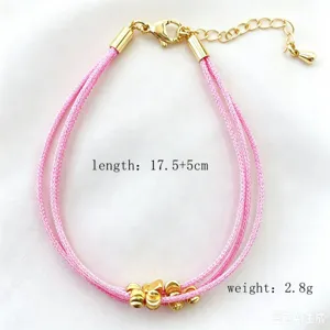 Vista dettagliata del bracciale in corda intrecciata multistrato rosa con perle dorate.