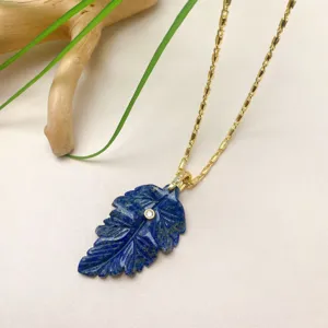 Gros plan détaillé d'un collier pendentif feuille en lapis-lazuli avec chaîne or.