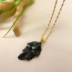 Gros plan détaillé du collier pendentif en feuille de cristal noir sculpté à la main.
