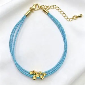 Bracciale in corda intrecciata blu a più fili con perline dorate e ciondolo a farfalla.