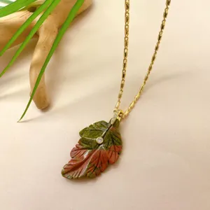 Gros plan détaillé du pendentif en pierre sculptée en forme de feuille avec chaîne or.