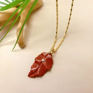 Vue détaillée du collier pendentif feuille sculpté rouge exquis avec une chaîne dorée.