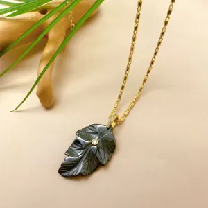 Collier pendentif feuille noire sculptée à la main avec chaîne dorée délicate et cristal brillant.