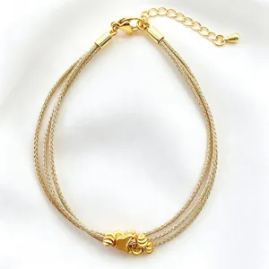 Dettaglio in primo piano del bracciale in filo d'oro multistrand con ciondolo centrale lucido.