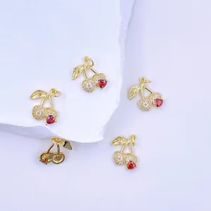Detailed close-up of shiny gold cherry pendants with sparkling zirconia and red heart stones.