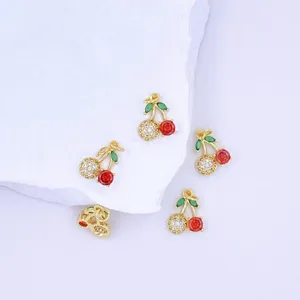 Closeup detail of cute gold cherry pendant charms with sparkling zirconia and vibrant red stones.