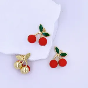 Detailed view of handmade red cherry charms and gold leaf DIY accessories for jewelry making.