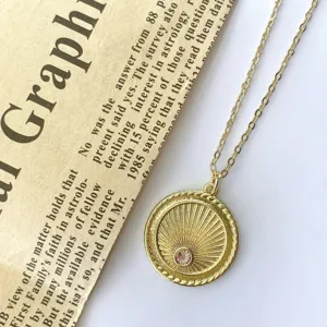 Vintage gold-plated sunburst coin necklace pendant with sparkling pink zircon detail close-up