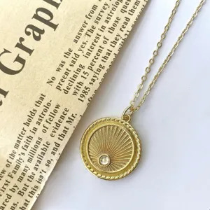 Gold vintage coin pendant necklace with sunburst design and sparkling zircon stone detail.