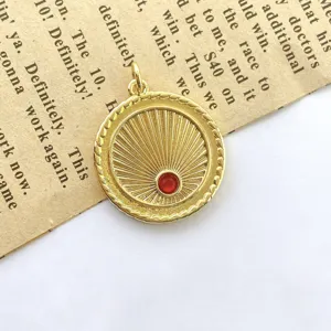 Close-up of retro gold sunburst pendant with red zircon on vintage paper background detail.