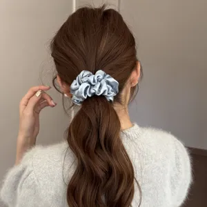 Close-up detail of light blue satin hair scrunchie with rhinestone accents for ponytails.