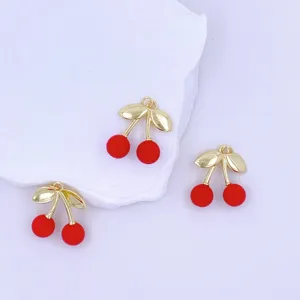 Close-up detail of cute red cherry charms with gold stems, perfect for DIY jewelry and crafts.