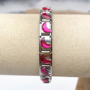 Detailed close-up of stainless steel Italian charm bracelet with red moon gemstone modules.