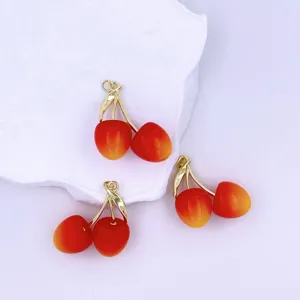 Detailed view of DIY red cherry charms featuring gold stems and gradient fruit design for handmade jewelry.