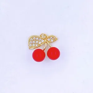 Gold-plated cherry pendant detail, featuring sparkly zirconia leaves and vivid red fruit.